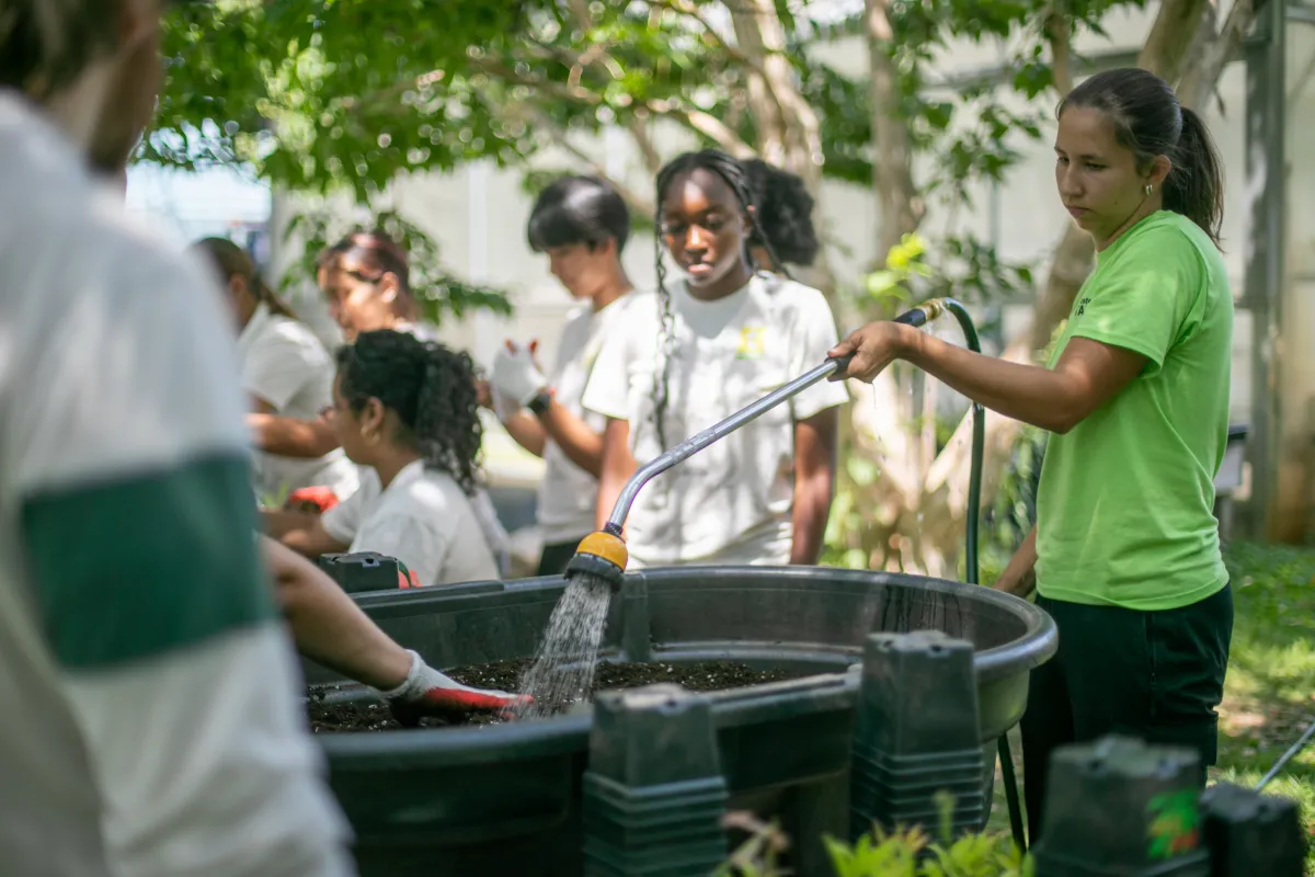Julia Beyer '26 holds a hose during a plant sale event with teens