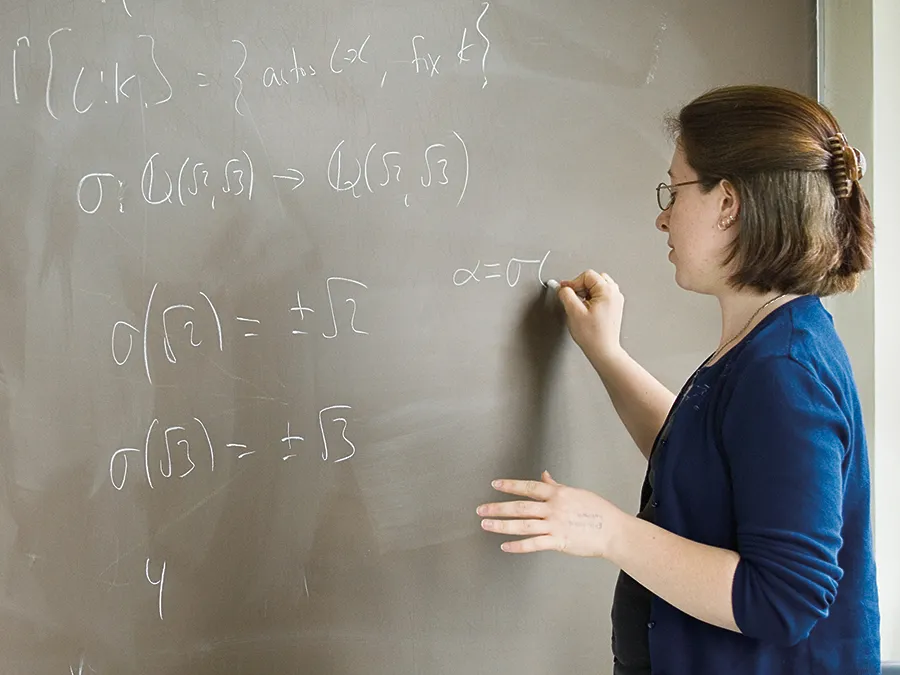Student working on a math equation at a blackboard