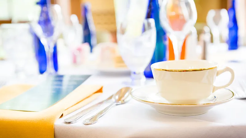 A close-up of a tea cup and a set table