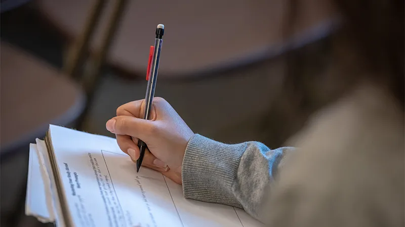 Image of student writing with pen in hand