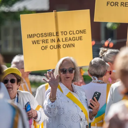 An alum at Reunion holding a yellow sign that reads “Impossible to clone, we’re in a league of our own.”