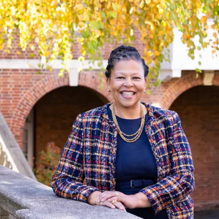 Sarah Willie-LeBreton leaning on a stone banister in the quad at Smith College