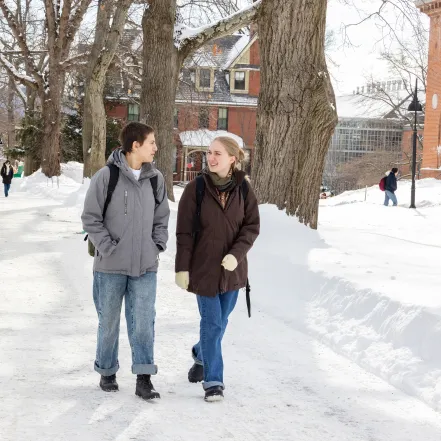Two students walk in the snow on campus