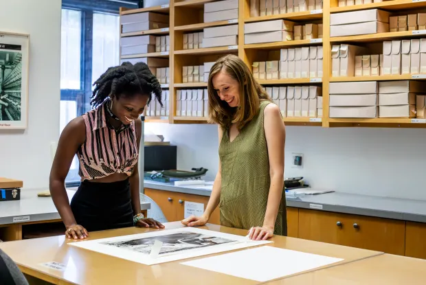 A student and supervisor looking at a photo on a table.