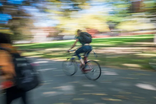 Motion-blurred photo of a student riding a bike on campus