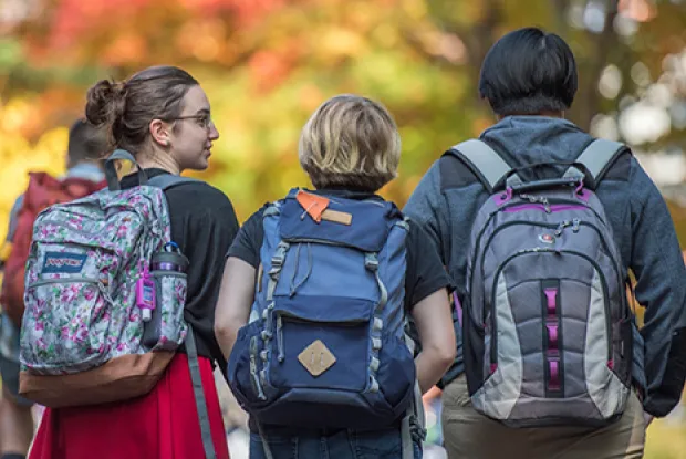 Three students with backpacks walking away from the camera